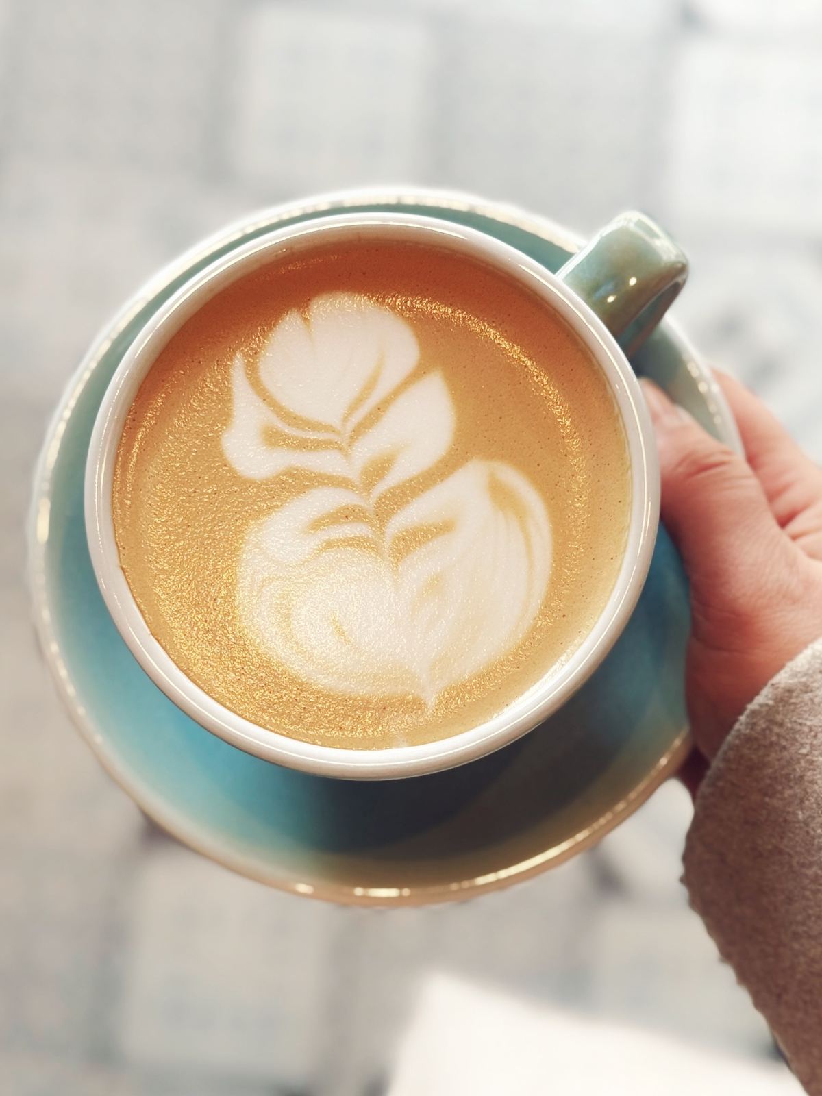 Cappuccino cu latte art într-o ceașcă turcoaz